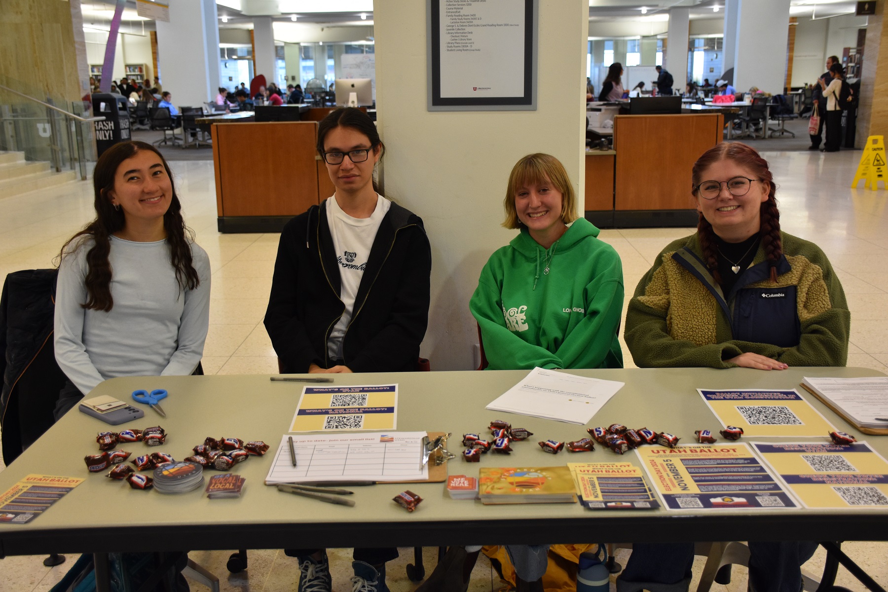 Students sit behind a table with voter registration materials