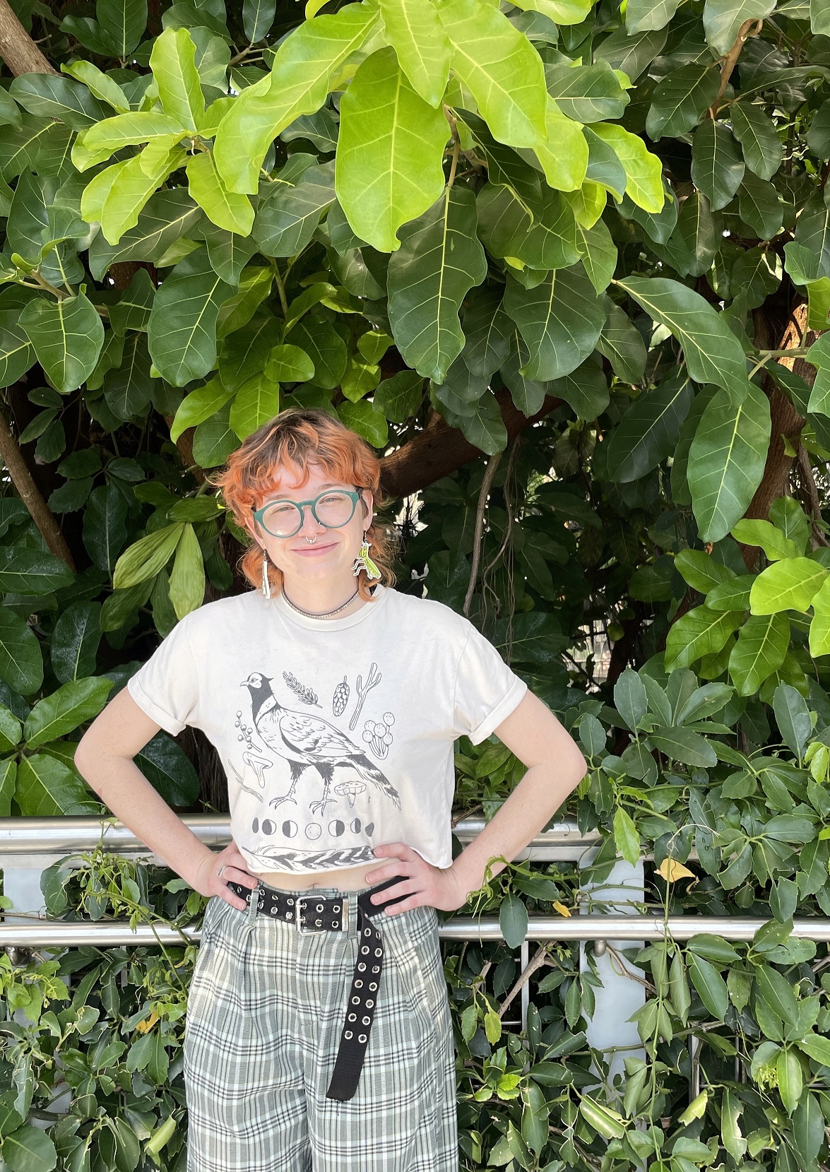 Student standing in front of plants with hands on hips